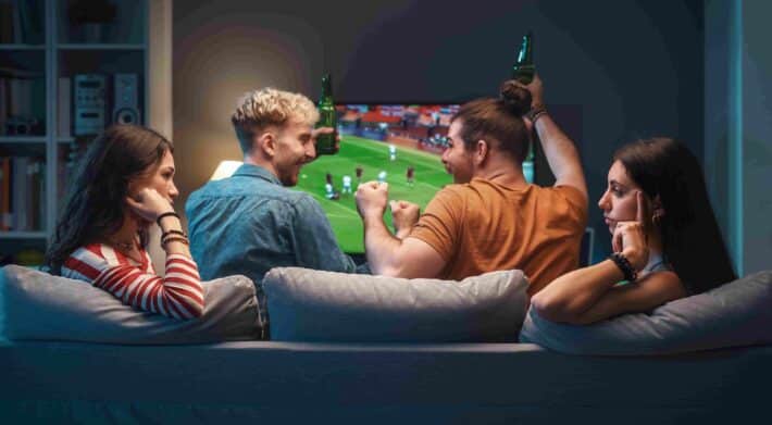girls talking while men are watching soccer on tv